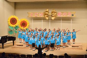 振り付けを交えて歌う団員たち、舞台は保護者有志の手作り