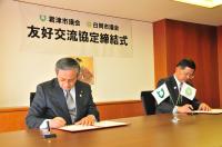 協定書にサインする両市議会正副議長 